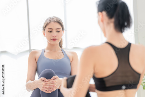 Two women confident training yoga. Athletic women in sportswear doing fitness stretching exercises at home in the living room. Sport and recreation concept. Yoga teacher is helping young woman.