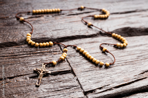Holy catholic rosary and a cross - wooden background