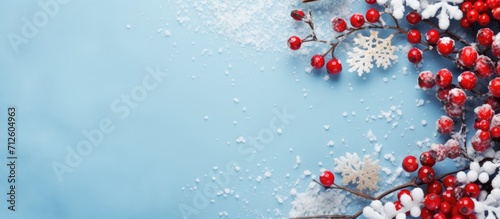 Holiday-themed arrangement with snowflake and berry frame on blue background. Festive concept. Overhead view.