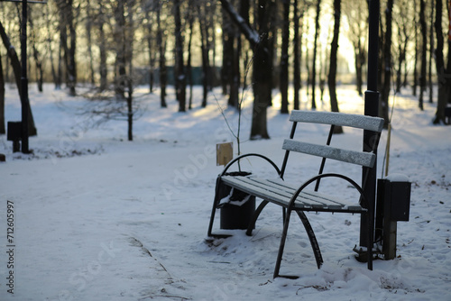 park bench on a winter alley at snowfall. bench with snow after snowstorm or in snow calamity in europe