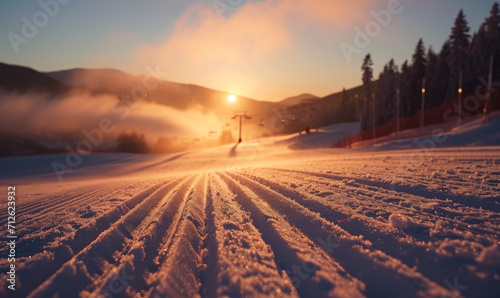 Sunrise over freshly groomed ski slopes in a winter landscape.