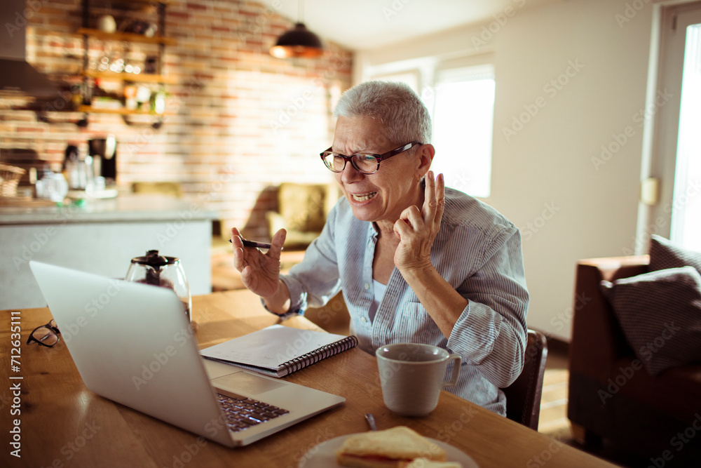 Senior woman working from home and taking notes Senior woman working from home and taking notes