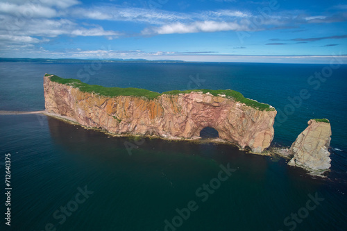 The beautiful colors, natural arch and shape of famous Perce Rock on the Gaspe Peninsula in Quebec Canada with it's red-pinkish colors from an aerial drone image