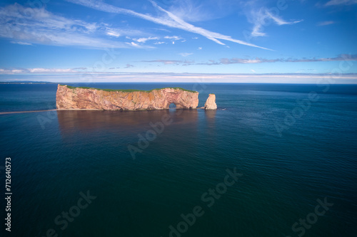 The beautiful colors, natural arch and shape of famous Perce Rock on the Gaspe Peninsula in Quebec Canada with it's red-pinkish colors from an aerial drone image photo