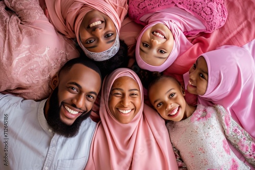 Happy Muslim family with smiling faces and traditional clothing seen from an overhead view, sharing a joyful moment together. photo