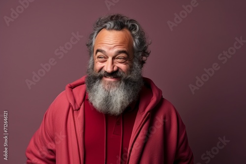 Portrait of a happy senior man with long gray beard and mustache in a red hoodie.