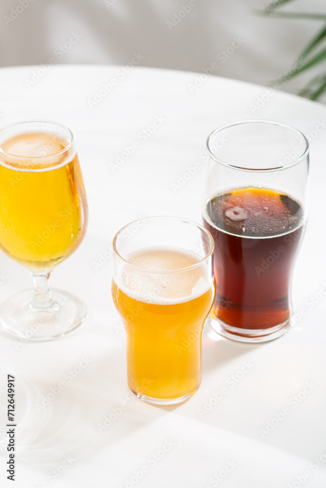 glasses with light beer and dark ale cider on white table glasses with light beer and dark ale cider on white table