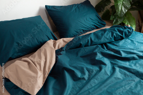 Cotton bed linen of two colors on the bed, pillow and blanket