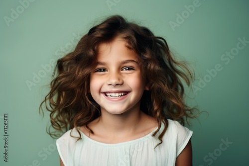 Portrait of a smiling little girl with long curly hair, studio shot