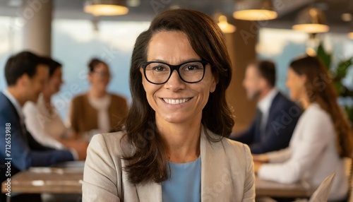 Candid shot of a smiling middle-aged woman with glasses in a casual business meeting, with a focus on her expressive joy