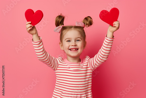 Excited little girl with heart cutouts celebrating Valentine's Day, joyful and smiling