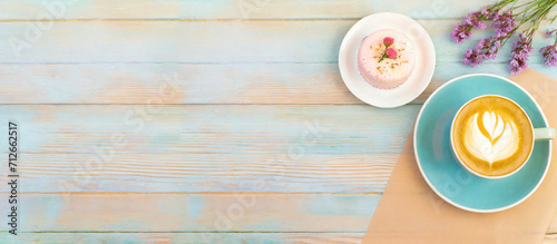 Kaffee und Kuchen auf einem Holztisch angerichtet in Pastellfarben 