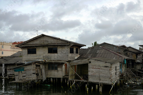 A coastal suburban neighborhood with long-abandoned and nearly collapsed houses on stilts near the sea © andimardila