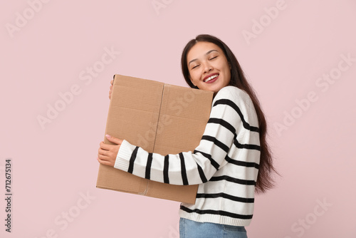 Pretty young woman with parcel on pink background © Pixel-Shot