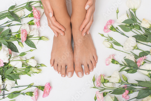 Fototapeta Naklejka Na Ścianę i Meble -  Beautiful female feet with flowers in the background.