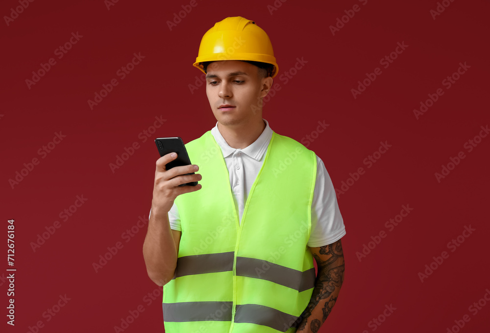 Young male engineer with smartphone on red background Young male engineer with smartphone on red background