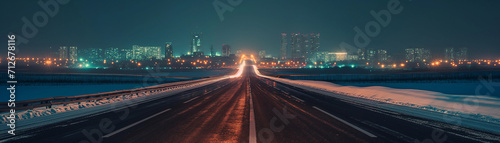 winter highway. city skyline at night. city lights. tall buildings and skyscrapers at night. dark winter night sky  snow covered sideways on a highway leading to the horizon. 