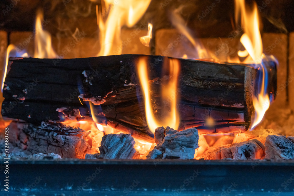 Looking into wood stove with firewood burning and hot coals below. Looking into wood stove with firewood burning and hot coals below.
