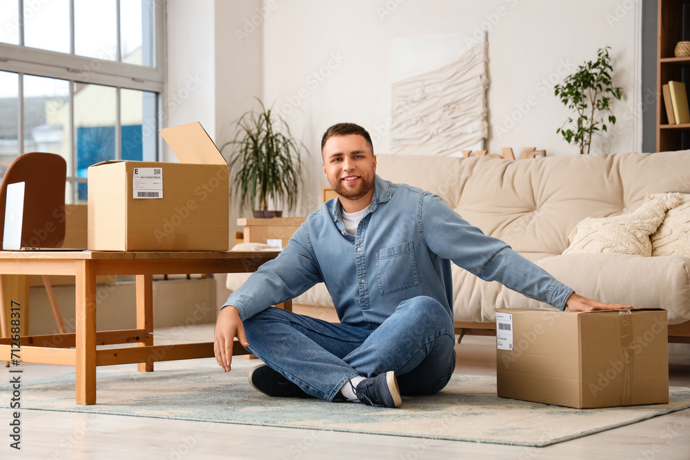 Young man with parcels sitting on floor at home Young man with parcels sitting on floor at home