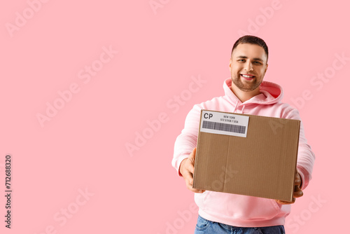 Young man with parcel on pink background © Pixel-Shot
