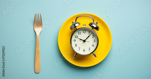 Top view alarm clock on lunch plate with knife and fork on table background. Morning Routine Top View Alarm Clock on Breakfast Table
