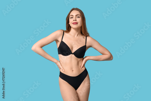 Attractive young woman in black underwear on blue background