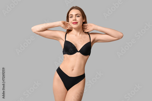 Sexy young woman in black underwear on light background