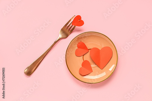 Composition with paper hearts, plate and fork on pink background. Valentine's day celebration