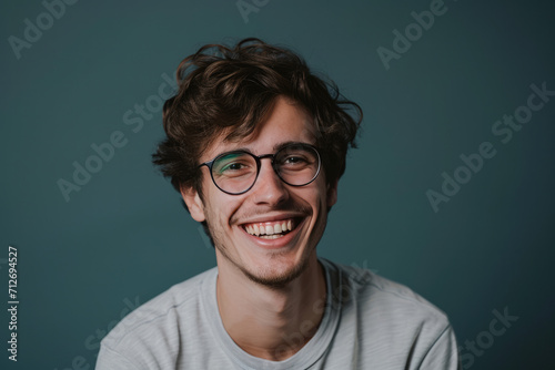 A young man wearing glasses is smiling for the camera