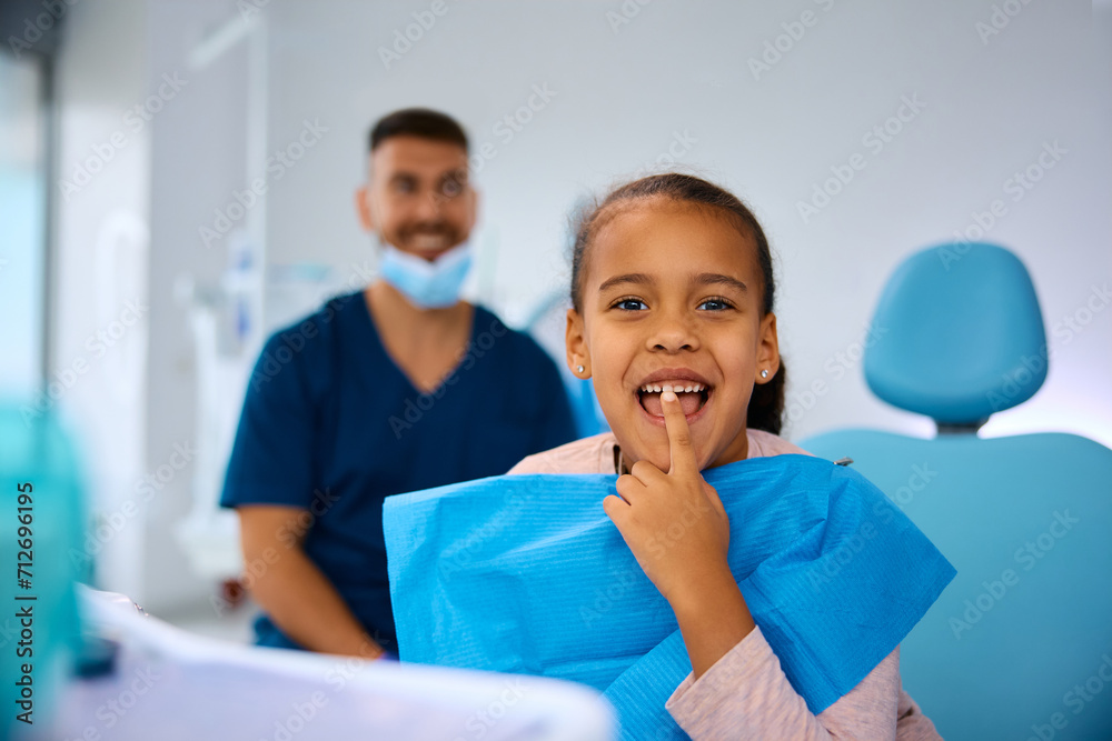 Happy black girl showing her teeth while sitting in dentist's chair and looking at camera. Happy black girl showing her teeth while sitting in dentist's chair and looking at camera.