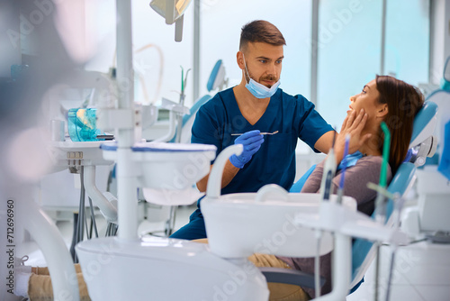 Young woman with toothache talks to her dentist during appointment at dental clinic.