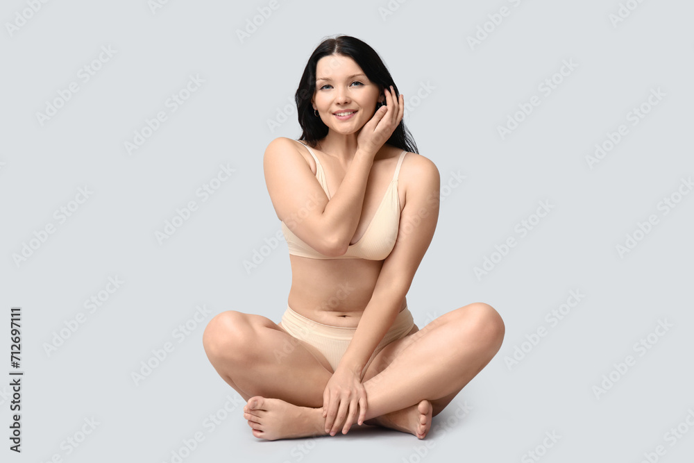 Body positive young woman in underwear sitting on light background Body positive young woman in underwear sitting on light background