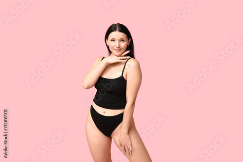 Body positive young woman in underwear on pink background