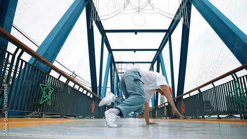 Professional break dancer perform street dance footstep at bridge. Asian hipster wear headphone while doing freeze pose. Break dancer, street dancer freestyle concept. Outdoor sport 2024. Sprightly. photo