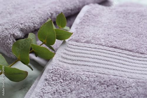Violet terry towels and eucalyptus branch on table, closeup