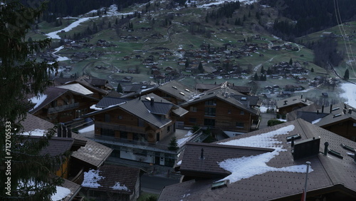 Swiss Alps view of traditional chalets with mountains covered in snow in background during winter ski season