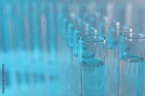 Laboratory analysis. Many glass test tubes on light blue background  closeup and space for text