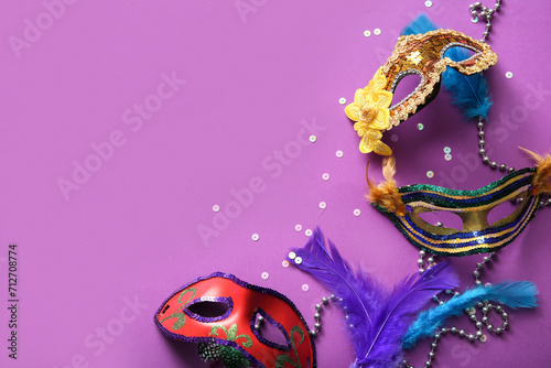 Carnival masks with feathers and beads for Mardi Gras celebration on purple background
