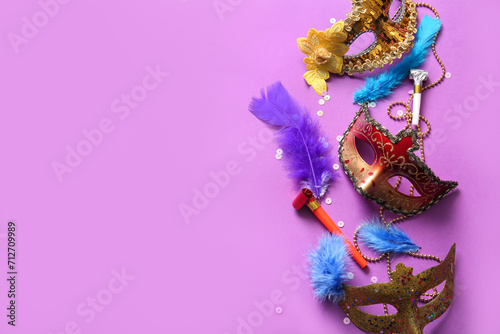 Carnival masks with party horns and feathers for Mardi Gras celebration on purple background
