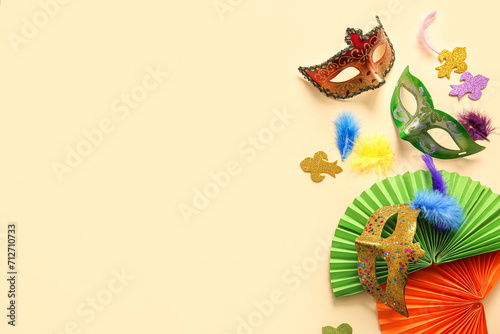 Carnival masks with feathers and paper fans for Mardi Gras celebration on beige background