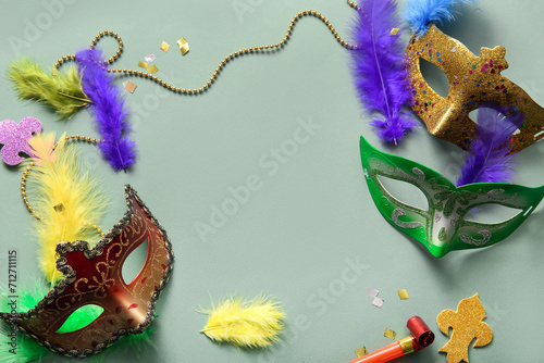 Frame made of carnival masks with party horn and decor for Mardi Gras celebration on green background