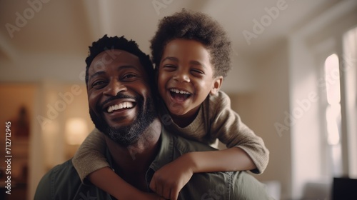 Happy black father and son playing on blurred background of living room photo