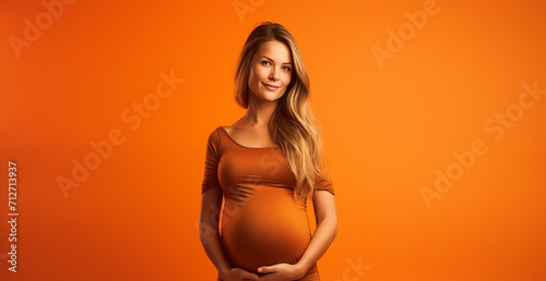 Belle femme enceinte debout sur fond orange, image avec espace pour texte photo