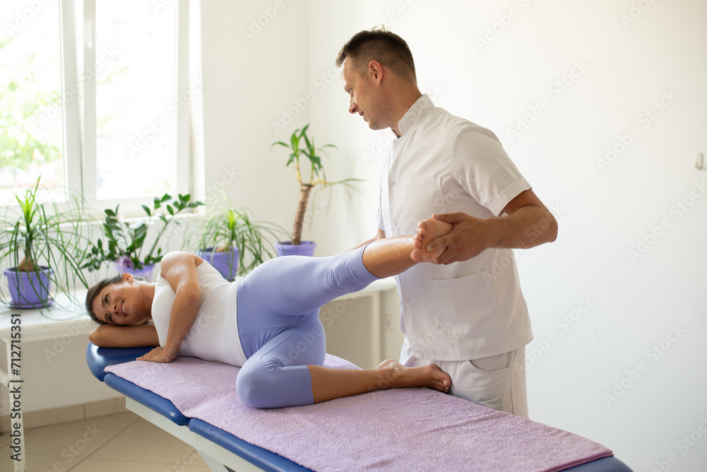 A young woman exercises with the help of physiotherapist during physiotherapy A young woman exercises with the help of physiotherapist during physiotherapy