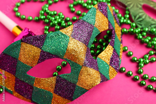 Carnival mask with decor for Mardi Gras celebration on pink background
