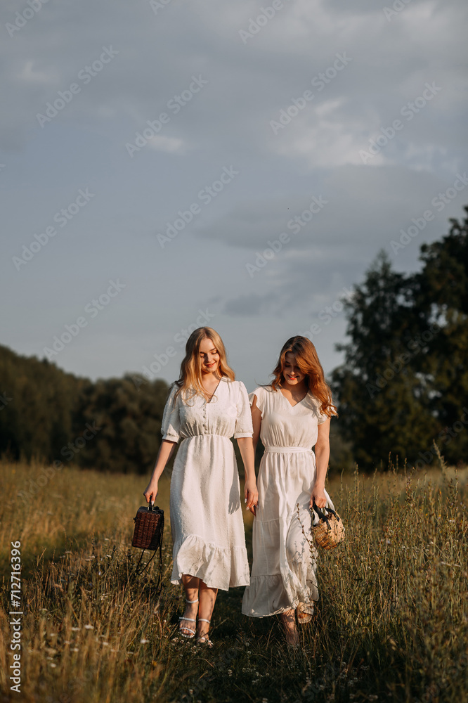 The image features two women wearing white dresses standing outdoors in a field. 5620 The image features two women wearing white dresses standing outdoors in a field. 5620