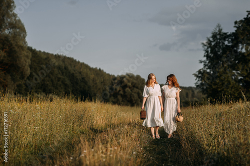 The image depicts two women walking in a field. 5619