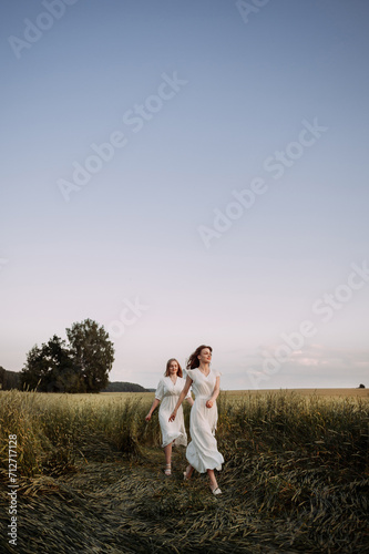 The image features two women wearing white dresses in an outdoor setting 5709.