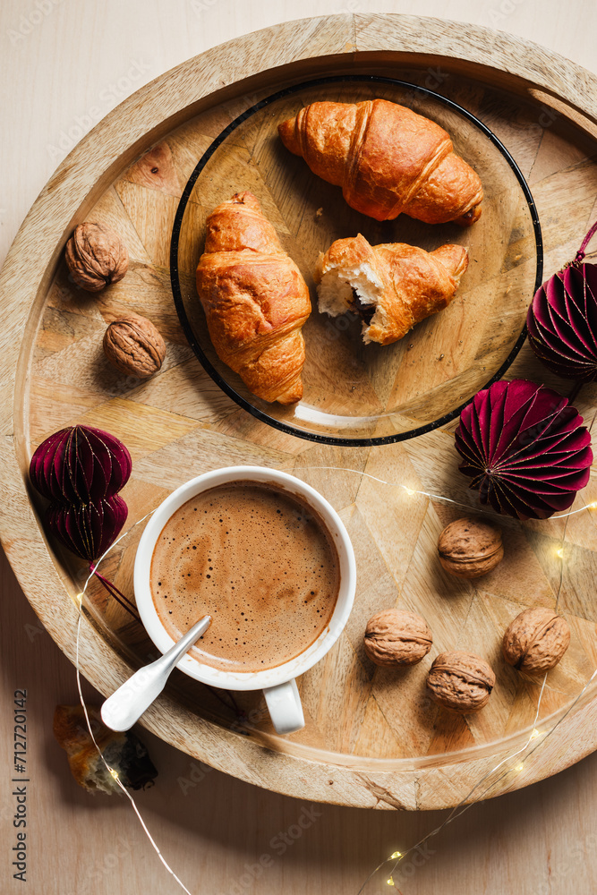 Cup of coffee, chocolate croissants on a wooden tray with Christmas decorations. Cup of coffee, chocolate croissants on a wooden tray with Christmas decorations.