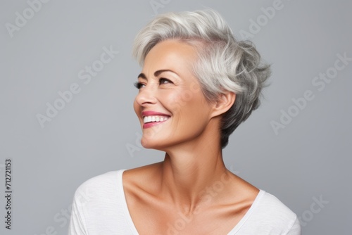 Portrait of a beautiful middle aged woman with short gray hair, over grey background